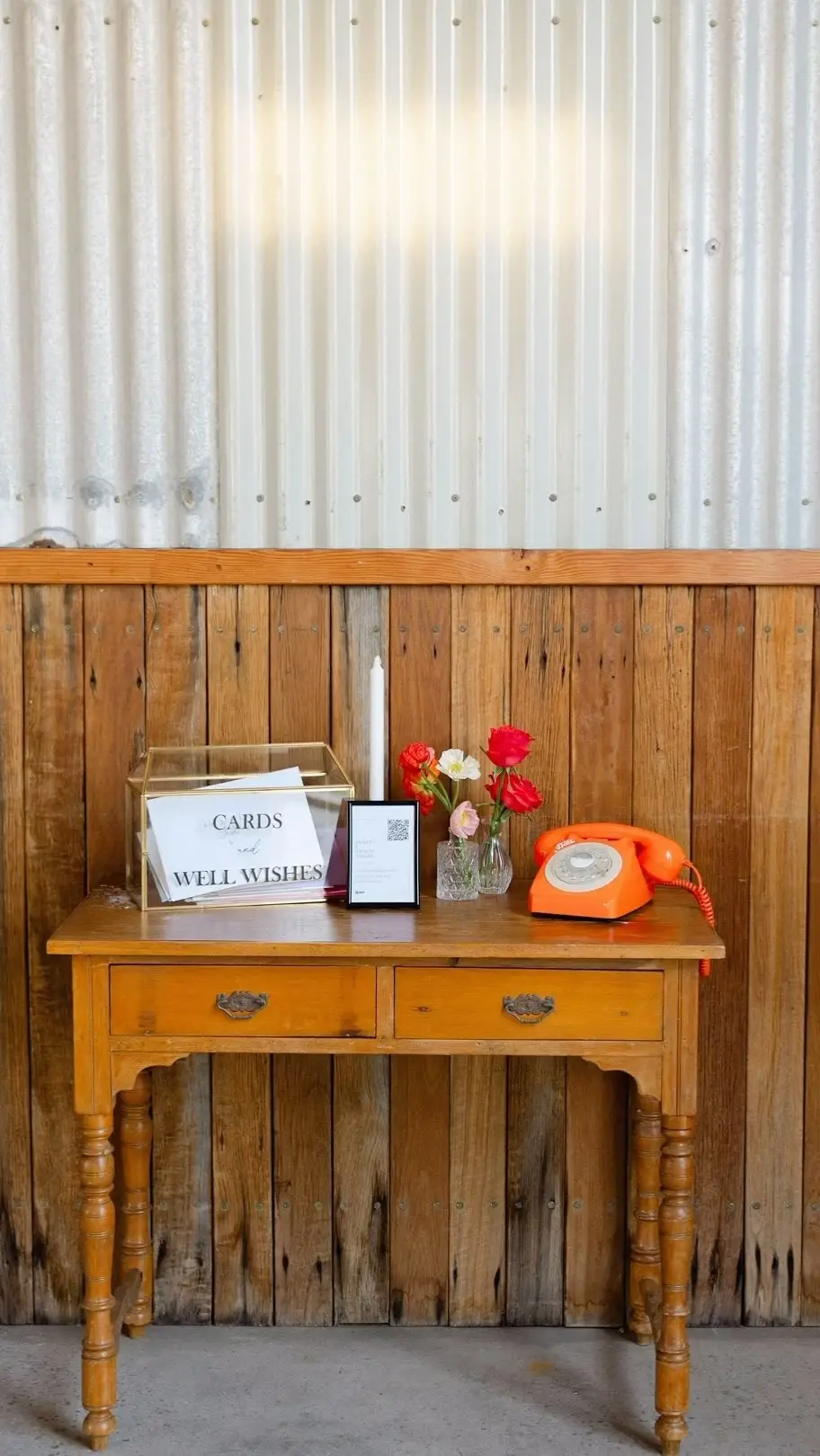 Small wooden table with an orange phone, a card box and flowers