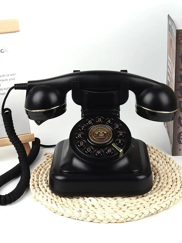 Black retro phone with a gold dial on a round woven stand