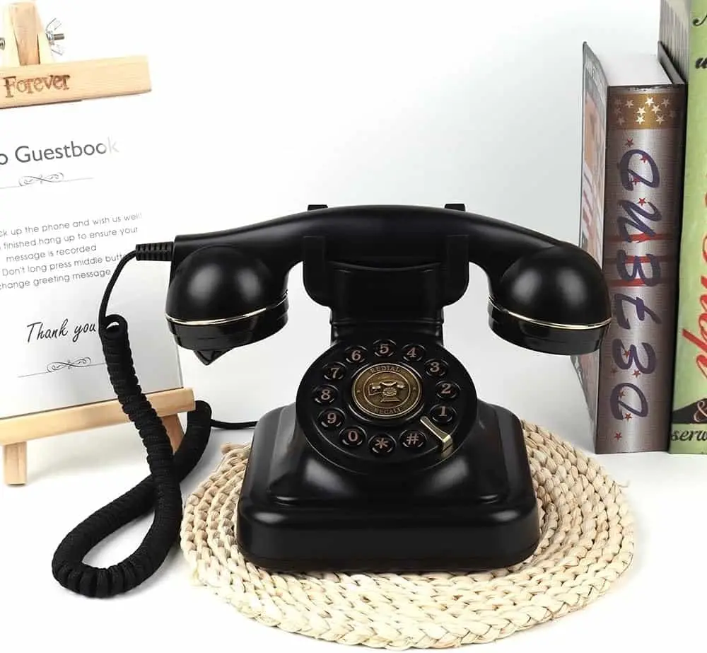 Black rotary phone on a woven stand, next to a sign with instructions